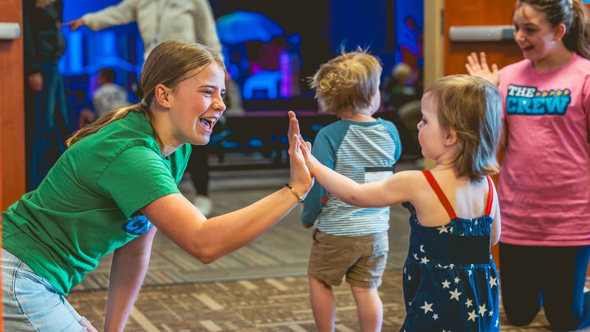 Student high-fiving toddler in Kids Ministry at Mission Hills Church