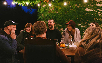 Group of friends laughing around a table outside